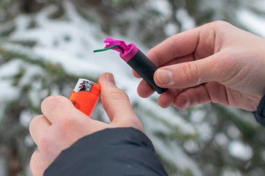 Guy kışın açık havada Flash Gürültülü Havai Fişek 'i ateşe veriyor. Gürültülü ve tehlikeli yeni yıl eğlencesi. Havai fişeklerle holiganlık. Halka Açık Yerlerdeki Petard 'ların Gürültüsü