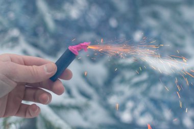 Bir elde yanan havai fişek. Kışın gündüz vakti Petard Outdoor tutan adam. Gürültülü ve tehlikeli yeni yıl eğlencesi. Havai fişeklerle holiganlık. Halka açık yerlerde havai fişek sesleri
