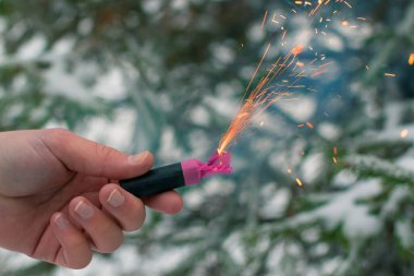 Bir elde yanan havai fişek. Kışın gündüz vakti Petard Outdoor tutan adam. Gürültülü ve tehlikeli yeni yıl eğlencesi. Havai fişeklerle holiganlık. Halka açık yerlerde havai fişek sesleri