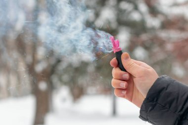 Bir elde yanan havai fişek. Kışın gündüz vakti Petard Outdoor tutan adam. Gürültülü ve tehlikeli yeni yıl eğlencesi. Havai fişeklerle holiganlık. Halka açık yerlerde havai fişek sesleri