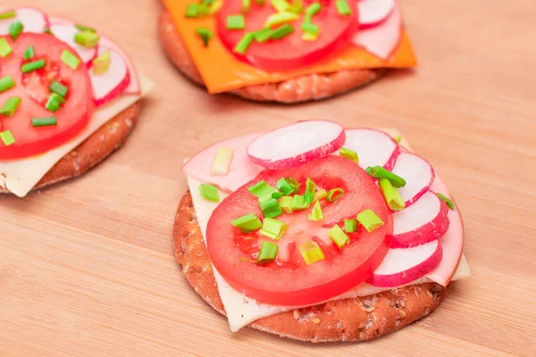 Crispy Cracker Sandwiches with Tomato, Sausage, Cheese, Green Onions and Radish on Cutting Board. Easy Breakfast. Quick and Healthy Sandwiches. Crispbread with Tasty Filling. Healthy Dietary Snack