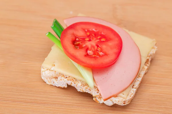 Rice Cake Sandwich with Tomato, Sausage, Green Onions and Cheese on Wooden Cutting Board. Easy Breakfast. Diet Food. Quick and Healthy Sandwiches. Crispbread with Tasty Filling. Healthy Dietary Snack