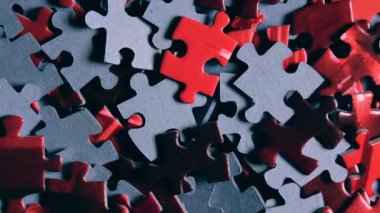 Saat Yönünde Yavaşça Dönen Renkli Bulmaca Parçalarının Arkaplanı - Üst Görünüm, Yakın Çekim. Tamamlanmamış Kırmızı ve Gri Yapbozun Yapbozu Düşük Anahtarlı Işık - Sağa Çevirme