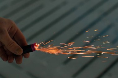 Firecracker 'ı kıvılcımla yakmak. Elinde Petard tutan bir adam. Gürültülü ve tehlikeli yeni yıl eğlencesi. Havai fişeklerle holiganlık. Halka açık yerlerde havai fişek sesleri