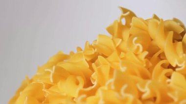 Pişmemiş Fusilli Pasta Yığını Beyaz Arkaplan 'a karşı dönüyor. Şişman ve Sağlıksız Yemek. Kuru Spiral makarna. İtalyan Kültür ve Mutfağı. Çiğ Altın Makarna