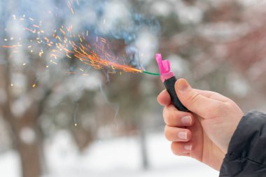 Bir elde yanan havai fişek. Kışın gündüz vakti Petard Outdoor tutan adam. Gürültülü ve tehlikeli yeni yıl eğlencesi. Havai fişeklerle holiganlık. Halka açık yerlerde havai fişek sesleri