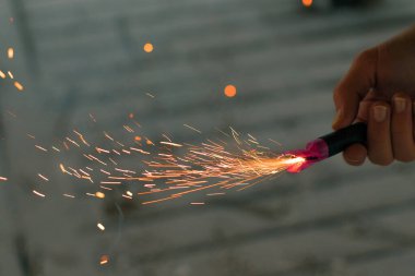 Firecracker 'ı kıvılcımla yakmak. Elinde Petard tutan bir adam. Gürültülü ve tehlikeli yeni yıl eğlencesi. Havai fişeklerle holiganlık. Halka açık yerlerde havai fişek sesleri