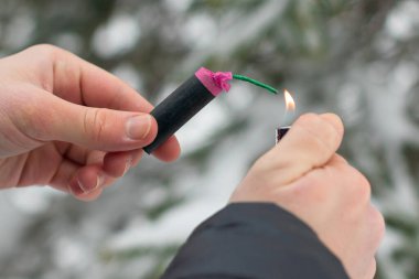 Guy kışın açık havada Flash Gürültülü Havai Fişek 'i ateşe veriyor. Gürültülü ve tehlikeli yeni yıl eğlencesi. Havai fişeklerle holiganlık. Halka Açık Yerlerdeki Petard 'ların Gürültüsü