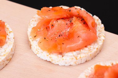 Lezzetli Rice Cake Sandviçleri ve Taze Somon Dilimleri Kesme Kurulu - Yakın plan. Kolay Kahvaltı ve Diyet Yemekler. Kırmızı balıklı çıtır ekmek. Sağlıklı Beslenme Atıştırması