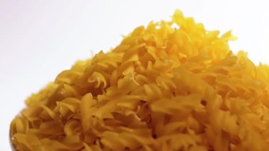 Pişmemiş Fusilli Pasta Yığını Beyaz Arkaplan 'a karşı dönüyor. Şişman ve Sağlıksız Yemek. Kuru Spiral makarna. İtalyan Kültür ve Mutfağı. Çiğ Altın Makarna