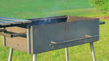 Burning Fire with Smoke Inside the Empty Brazier in Summer in the Daytime Outdoors. Preparing for Barbecue Cooking or Kebab Grilling. Kindling Coals in the Mangal - Static Shot, Slow Motion