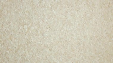 Kuru, pişmemiş, beyaz pirinç arka planı sola doğru dönüyor. Çiğ Uzun Taneli Pirinç. Asya mutfağı ve kültürü. Sağlıklı beslenme malzemeleri. Diyet Yemekler