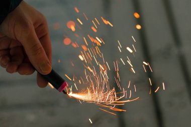 Firecracker 'ı kıvılcımla yakmak. Elinde Petard tutan bir adam. Gürültülü ve tehlikeli yeni yıl eğlencesi. Havai fişeklerle holiganlık. Halka açık yerlerde havai fişek sesleri