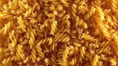 Pişmemiş Fusilli ve Chifferi Rigati Pasta Üst Manzara, Alçak Anahtar Işığı. Şişman ve Sağlıksız Yemek. Klasik Kuru Makarna, Dönen Arka plan. Raw Different Macaroni Makarna Dokusunu Sola Döndür