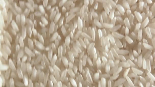 乾燥調理されていない白米の背景をゆっくりと下に移動 トップビュー 低キーライト 生の長粒米を散布 アジア料理と文化 健康的な食材 — ストック動画