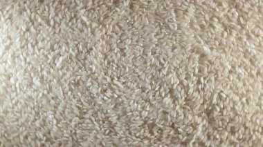 Kuru pişmemiş beyaz pirinç arka planı sola dönüyor - Üst Manzara, alçak anahtar ışığı. Çiğ Uzun Taneli Pirinç. Asya mutfağı ve kültürü. Sağlıklı beslenme malzemeleri. Diyet Yemekler