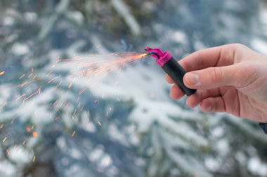 Bir elde yanan havai fişek. Kışın gündüz vakti Petard Outdoor tutan adam. Gürültülü ve tehlikeli yeni yıl eğlencesi. Havai fişeklerle holiganlık. Halka açık yerlerde havai fişek sesleri