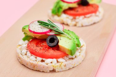 Avokado, domates, süzme peynir, zeytin ve turplu pirinç keki sandviçi tahtada. Kolay Kahvaltı 'da. Diyet yemek. Hızlı ve sağlıklı sandviçler. Lezzetli Çıtır Ekmek