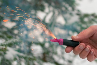 Bir elde yanan havai fişek. Kışın gündüz vakti Petard Outdoor tutan adam. Gürültülü ve tehlikeli yeni yıl eğlencesi. Havai fişeklerle holiganlık. Halka açık yerlerde havai fişek sesleri