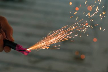 Firecracker 'ı kıvılcımla yakmak. Elinde Petard tutan bir adam. Gürültülü ve tehlikeli yeni yıl eğlencesi. Havai fişeklerle holiganlık. Halka açık yerlerde havai fişek sesleri