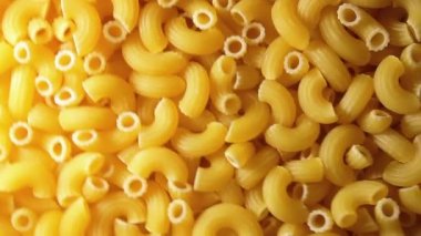 Uncooked Chifferi Rigati Pasta - Top View. Fat and Unhealthy Food. Classic Dry Macaroni, Slowly Rotating Background. Italian Culture and Cuisine. Raw Golden Pasta Texture - RIght Angular Rotation