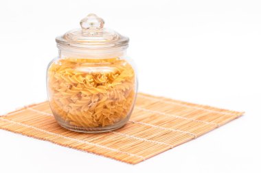 Beyaz Arkaplanda Cam Kavanozda Pişmemiş Fusilli Makarna. Çiğ ve kuru makarna. Sağlıksız ve şişman yiyecekler. İtalyan Kültürü
