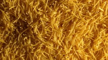 Saat Yönünde Yavaşça Dönen Pişmemiş Eriştelerin Arkaplanı - Üst Görünüm, Yakın Çekim. Kuru Vermicelli Dönüşü dokusu. Low Key Light ile Çiğ Makarna - Sağ Döndürme