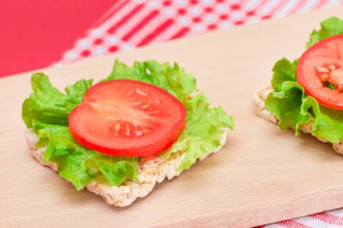 Domatesli pirinçli sandviç ve tahta kesim tahtasında marul. Kolay Kahvaltı 'da. Diyet yemek. Hızlı ve sağlıklı sandviçler. Lezzetli dolgulu kızarmış ekmek. Sağlıklı Beslenme Atıştırması