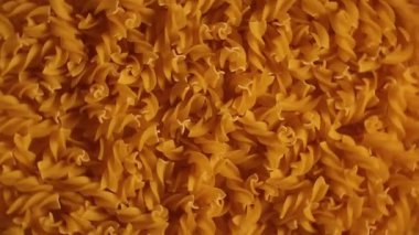 Pişmemiş Fusilli Makarna - Üst Görünüm, Düşük Anahtar Işığı. Şişman ve Sağlıksız Yemek. Kuru Spiral makarna, döner arka plan. İtalyan Kültür ve Mutfağı. Çiğ Altın Makarna deseni. Sağ Çevirme