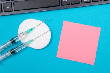 Aşılama, Bağışıklık Bilimi veya Yeniden Aşılama Konsepti - Bir Hastane veya Klinikte Mavi Masada Yatan İki Tıbbi Tek Kullanım Şırıngası. Boş Pembe Yapışkan Not - Uzayı Kopyala ile Moklonla