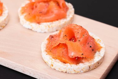 Lezzetli Rice Cake Sandviçleri ve Taze Somon Dilimleri Kesme Kurulu - Yakın plan. Kolay Kahvaltı ve Diyet Yemekler. Kırmızı balıklı çıtır ekmek. Sağlıklı Beslenme Atıştırması