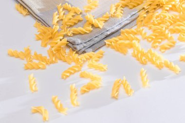 Beyaz Masaya Pişmemiş Fusilli Makarna Dağılmış. Çiğ ve kuru makarna. Şişman ve Sağlıksız Yemekler