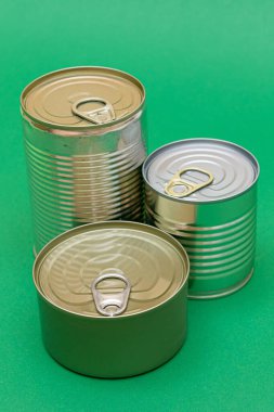 Yeşil Arkaplanda Boş Kenarlı İstiflenmiş Teneke Kutular Grubu. Konserve yiyecekler. Güvenli ve uzun vadeli yiyecek depolamak için farklı alüminyum kutular. Çelik Mühürlü Yiyecek Depolama Kutuları