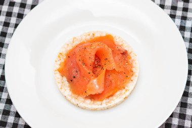 Lezzetli Rice Cake Sandviçi ve beyaz tabakta taze somon dilimleri. Kolay Kahvaltı ve Diyet Yemekler. Kırmızı balıklı çıtır ekmek. Sağlıklı Beslenme Atıştırması