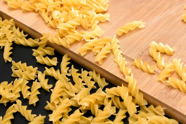 Ungekochte Fusilli Pasta Auf Holzbrett Und Schwarzem Tisch Verstreut Rohe — Stockfoto