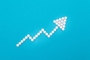 Global Eczacılık Endüstrisi ve Tıbbi Ürünler - Mavi Arkaplanda Beyaz Haplardan Yapılan Upward Arrow