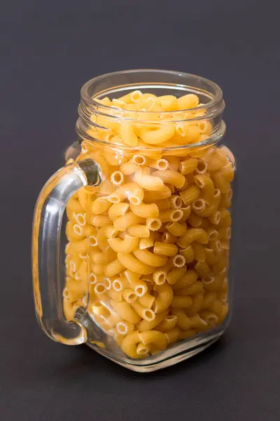 未烹调的Chifferi Rigati Pasta Glass Jar Black Background 脂肪和不健康的食物 经典的干通心粉 意大利文化与烹饪 — 图库照片