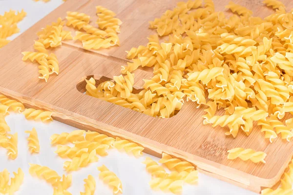 Ungekochte Fusilli Pasta Auf Holzbrett Und Weißem Tisch Verstreut Rohe — Stockfoto