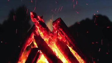 Big Burning Campfire in Early Morning or Evening against the Blue Sky. Wood on Fire. Flying Sparks. Travel and Tourism Concept. Giant Flaming Bonfire at Summer - Static Shot, Slow Motion