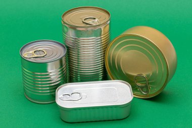 Yeşil Arkaplanda Boş Kenarlı İstiflenmiş Teneke Kutular Grubu. Konserve yiyecekler. Güvenli ve uzun vadeli yiyecek depolamak için farklı alüminyum kutular. Çelik Mühürlü Yiyecek Depolama Kutuları