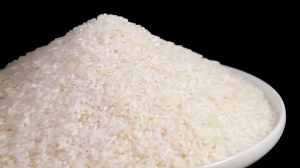 Dry Uncooked White Rice Heap White Plate Rotating Black Background — Vídeo de Stock