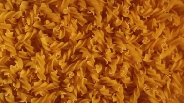 Pişmemiş Fusilli Makarna - Üst Görünüm, Düşük Anahtar Işığı. Şişman ve Sağlıksız Yemek. Kuru Spiral Makarna, Yavaşça Dönen Arkaplan. İtalyan Kültür ve Mutfağı. Çiğ Altın Makarna deseni. Sağ Çevirme