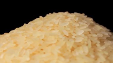 Dry Uncooked Parboiled Rice Heap Rotating against Black Background. A Pile of Raw Long Grain Rice. Asian Cuisine and Culture. Healthy Eating Ingredients. Diet Food
