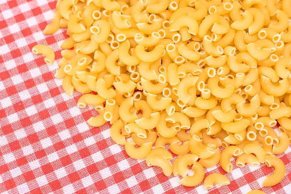 撒在红格子毛巾上的未煮熟的Chifferi Rigati Pasta 脂肪和不健康的食物 一大杯经典的干通心粉 意大利文化与烹饪 Raw Pasta — 图库照片