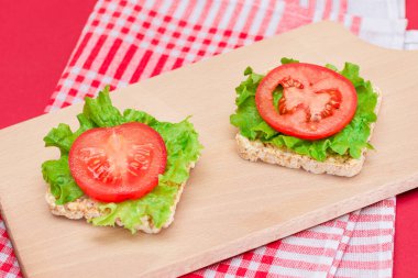 Domatesli pirinçli sandviç ve tahta kesim tahtasında marul. Kolay Kahvaltı 'da. Diyet yemek. Hızlı ve sağlıklı sandviçler. Lezzetli dolgulu kızarmış ekmek. Sağlıklı Beslenme Atıştırması