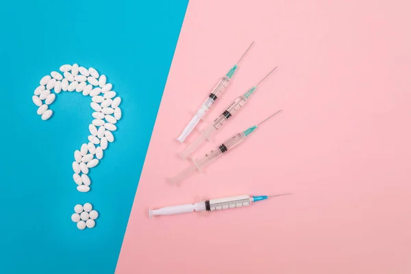 stock image Vaccination Scepticism. Question Mark Made from White Pills and Tablets with Medical Syringe, Lying on Split Blue and Pink Background. Global Pharmaceutical Industry and Medicinal Products