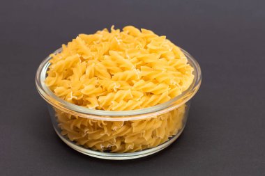 Kara Arkaplanda Cam Kavanoz 'da pişmemiş Fusilli Makarna. Şişman ve Sağlıksız Yemek. Klasik kuru sarmal makarna. İtalyan Kültür ve Mutfağı. Çiğ Makarna