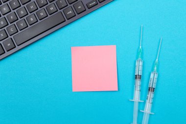 Aşılama, Bağışıklık Bilimi veya Yeniden Aşılama Konsepti - Bir Hastane veya Klinikte Mavi Masada Yatan İki Tıbbi Tek Kullanım Şırıngası. Boş Pembe Yapışkan Not - Uzayı Kopyala ile Moklonla