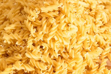 Tahta tahtada ve beyaz masada pişmemiş Fusilli Makarna. Çiğ ve kuru makarna. Şişman ve Sağlıksız Yemekler