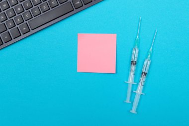 Aşılama, Bağışıklık Bilimi veya Yeniden Aşılama Konsepti - Bir Hastane veya Klinikte Mavi Masada Yatan İki Tıbbi Tek Kullanım Şırıngası. Boş Pembe Yapışkan Not - Uzayı Kopyala ile Moklonla